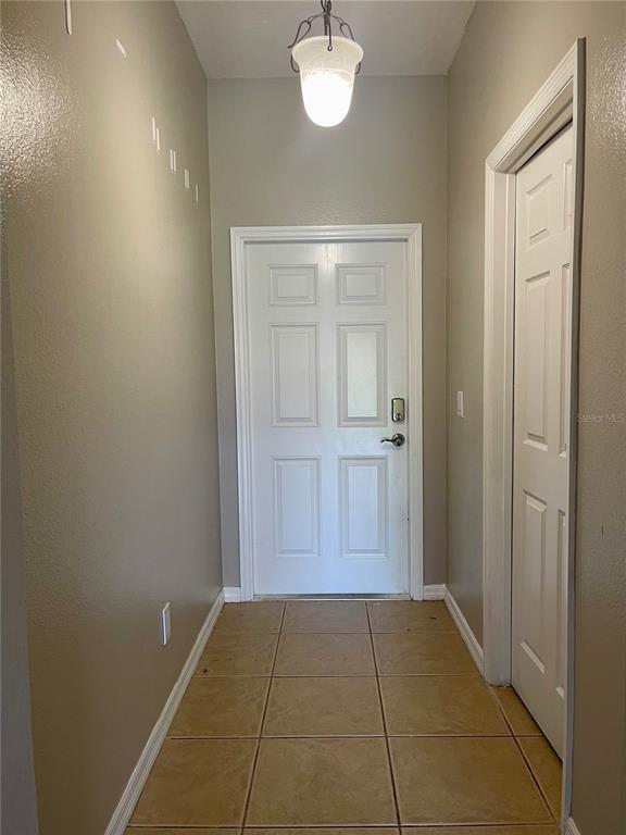 A hallway with tan tile flooring, a white front door, and a white closet door — 1251 LONG OAK WAY, SANFORD, FL
