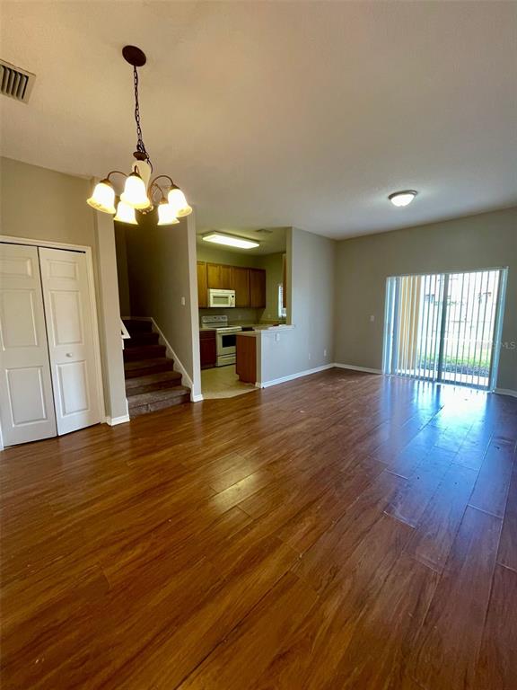 An open-concept living area features wood-look flooring, a chandelier, and an adjacent kitchen with stairs — 1251 LONG OAK WAY, SANFORD, FL