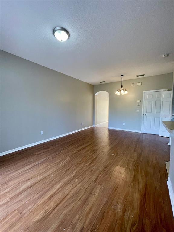 An empty room features wood-look flooring, light gray walls, a ceiling light, and a chandelier — 1251 LONG OAK WAY, SANFORD, FL