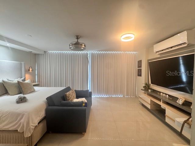A bedroom features a bed, a sofa, a large wall-mounted television, and floor-to-ceiling curtains — Ocean Drive 100 UNIT 806, LUQUILLO, PR