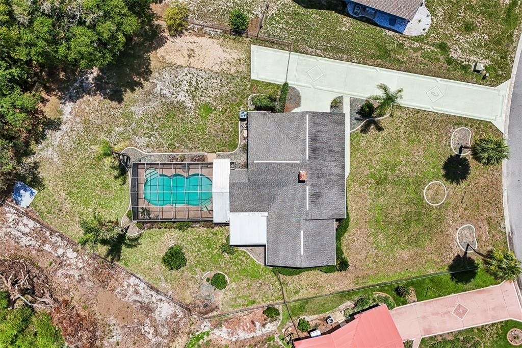 An aerial view shows a house with a screened-in pool, a driveway, and surrounding lawn — 5234 MAGNOLIA TERRACE, FRUITLAND PARK, FL
