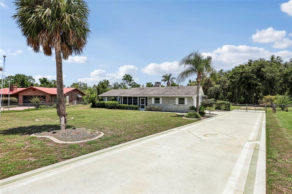 A single-story brick house with a long concrete driveway and two palm trees — 5234 MAGNOLIA TERRACE, FRUITLAND PARK, FL