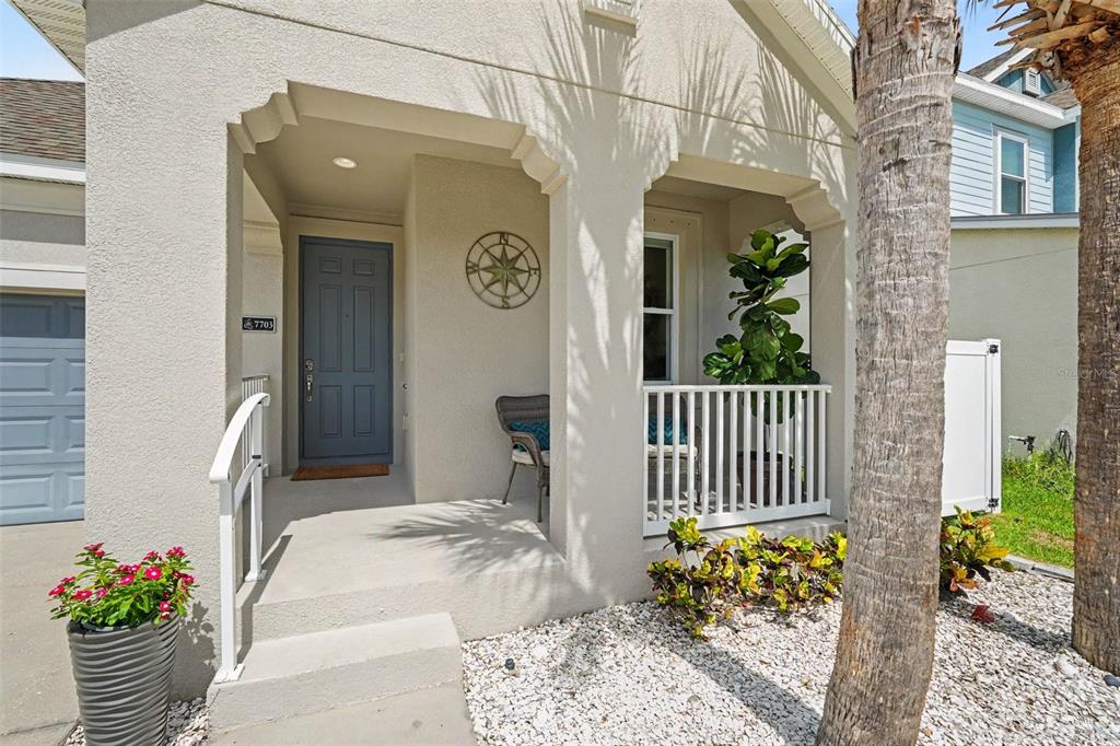 A front porch with a blue door, white railing, and a compass wall decoration — 7703 S SPARKMAN STREET, TAMPA, FL