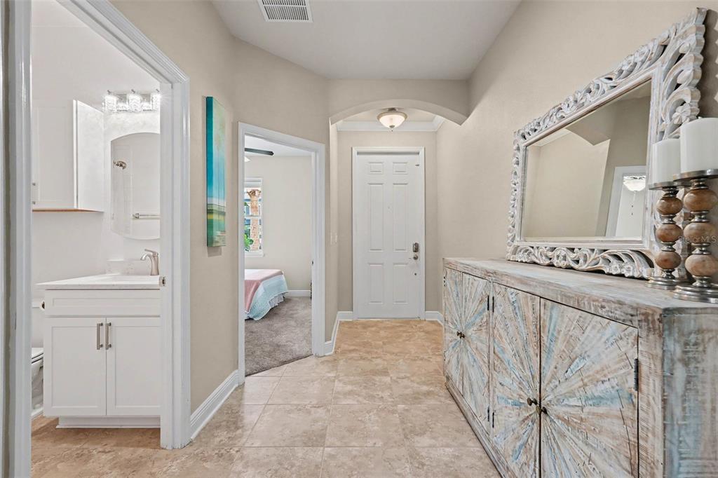 A tiled entryway features a white cabinet with a large ornate mirror and two doorways — 7703 S SPARKMAN STREET, TAMPA, FL