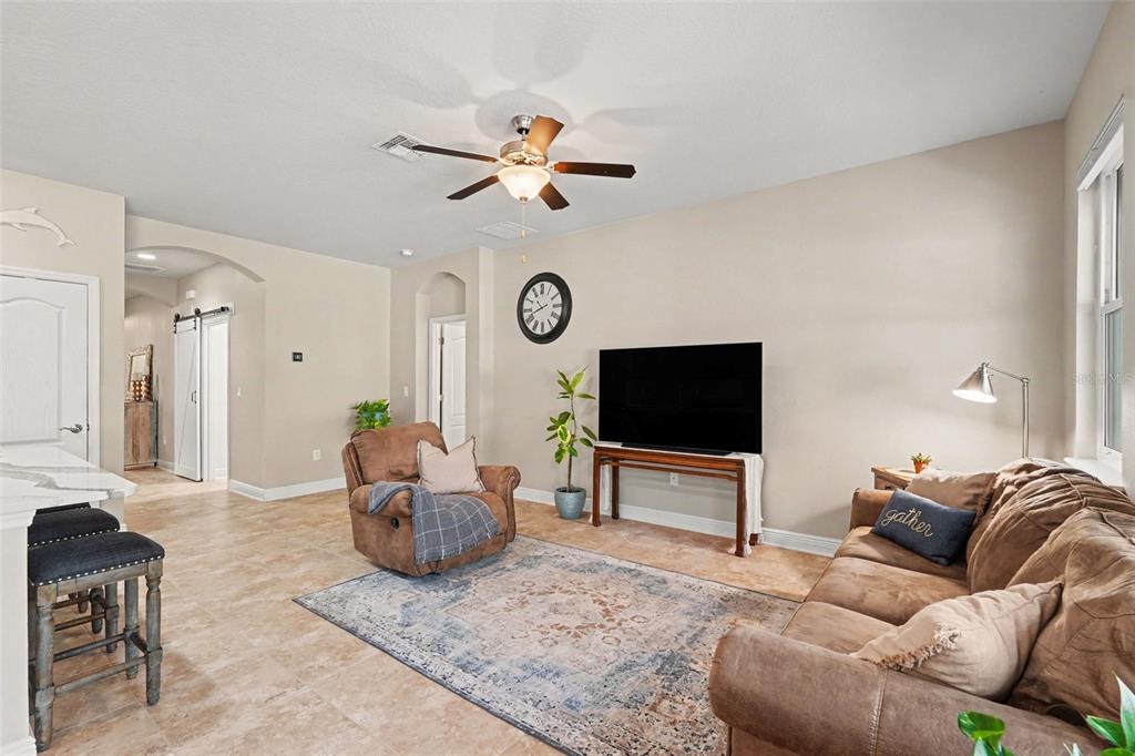 A living room features tile floors, a ceiling fan, a television, and brown furniture — 7703 S SPARKMAN STREET, TAMPA, FL