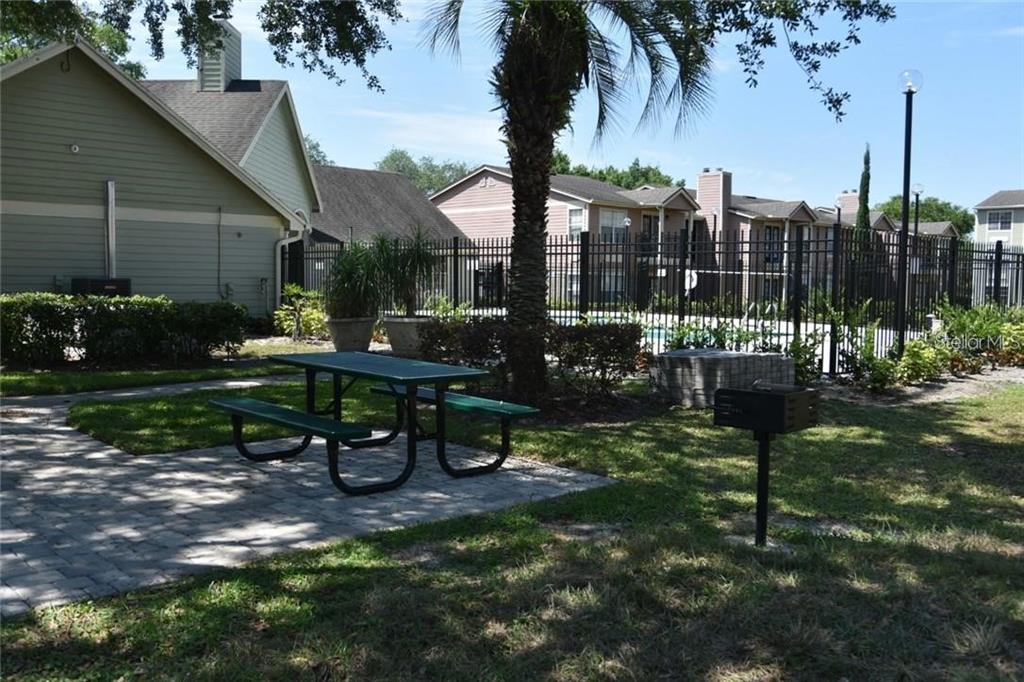 A green picnic table sits on a paved patio next to a charcoal grill outdoors — 2550 N ALAFAYA TRAIL UNIT 2111, ORLANDO, FL