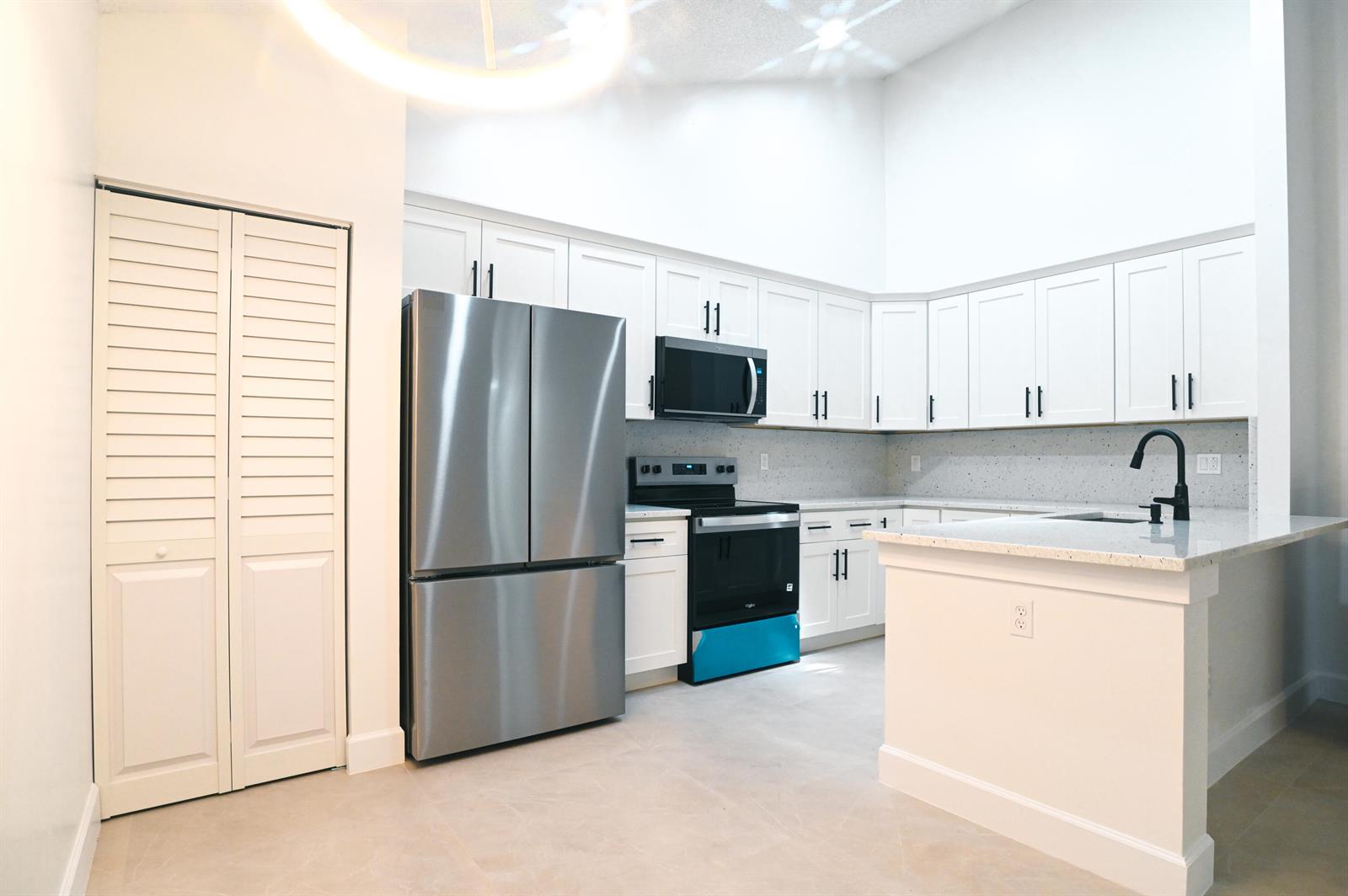 A kitchen features white cabinetry, stainless steel appliances, a granite countertop, and a kitchen island — 1148 Summit Trail Circle # D, West Palm Beach FL 33415, WEST PALM BEACH, FL