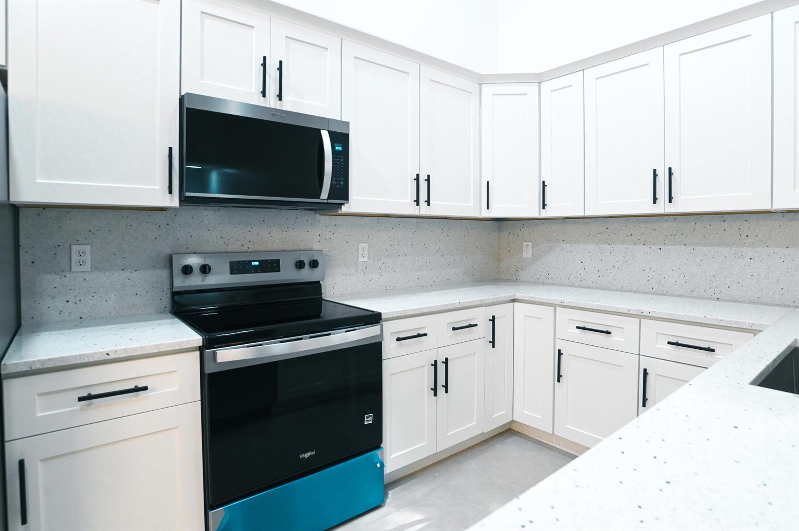 A modern kitchen features white shaker cabinets, speckled countertops, and black stainless steel appliances — 1148 Summit Trail Circle # D, West Palm Beach FL 33415, WEST PALM BEACH, FL