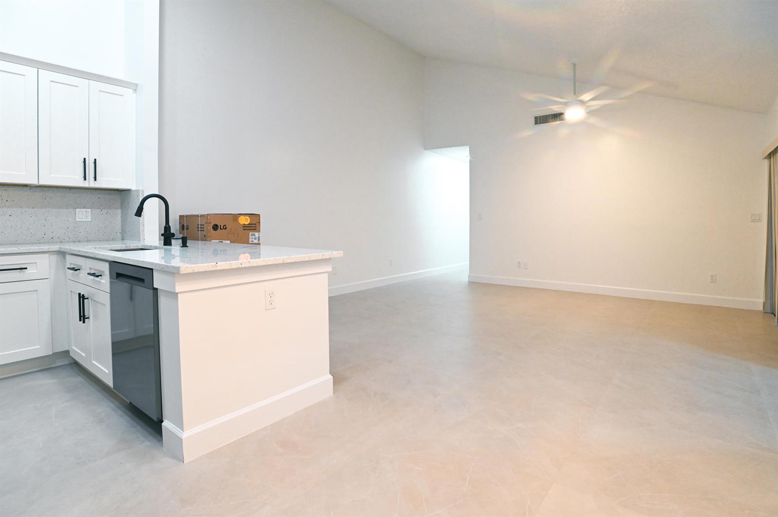 A kitchen with white cabinets and a quartz island opens into a large living area — 1148 Summit Trail Circle # D, West Palm Beach FL 33415, WEST PALM BEACH, FL