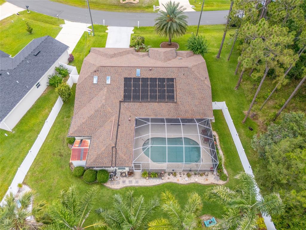 An aerial view shows a house with a solar-heated pool, screened lanai, and fenced yard — 29 WOODHOLME LANE, PALM COAST, FL