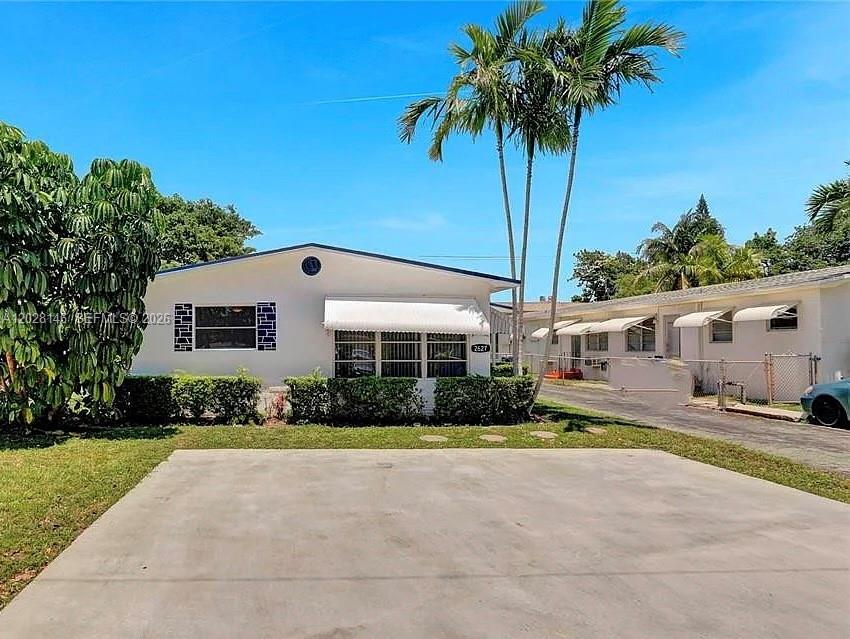 A single-story house with a concrete driveway, white exterior, and palm trees in the front — 2627 Lincoln St, Hollywood FL 33020, HOLLYWOOD, FL