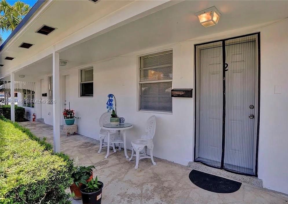 A covered patio features a small bistro set, potted plants, and a screen door — 2627 Lincoln St, Hollywood FL 33020, HOLLYWOOD, FL