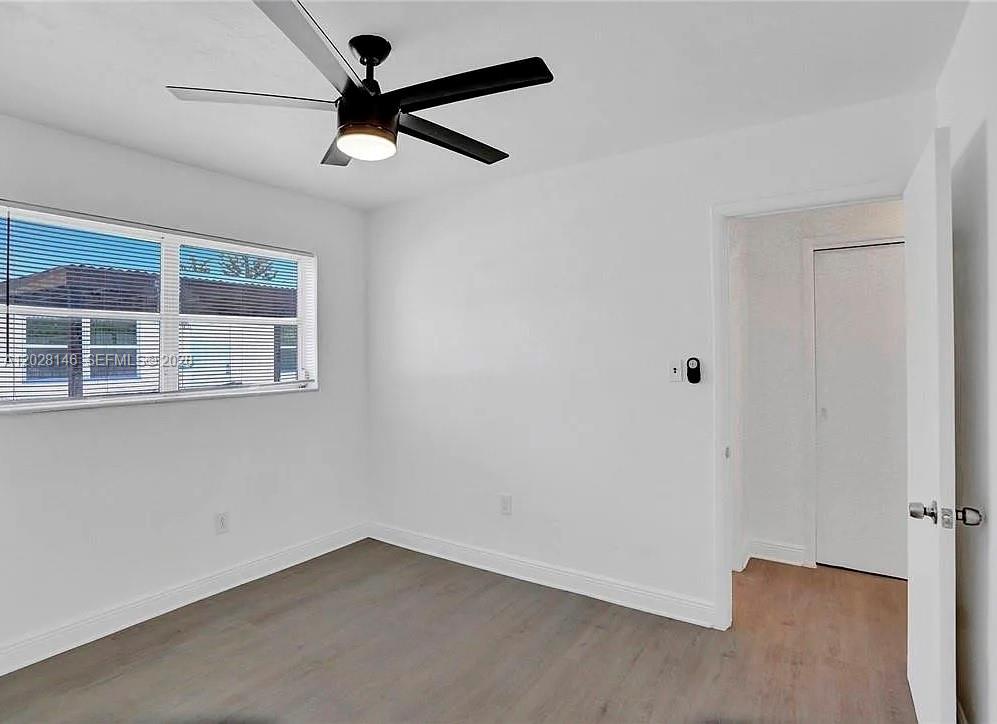 This bedroom features white walls, wood-look flooring, a ceiling fan, and a window with blinds — 2627 Lincoln St, Hollywood FL 33020, HOLLYWOOD, FL