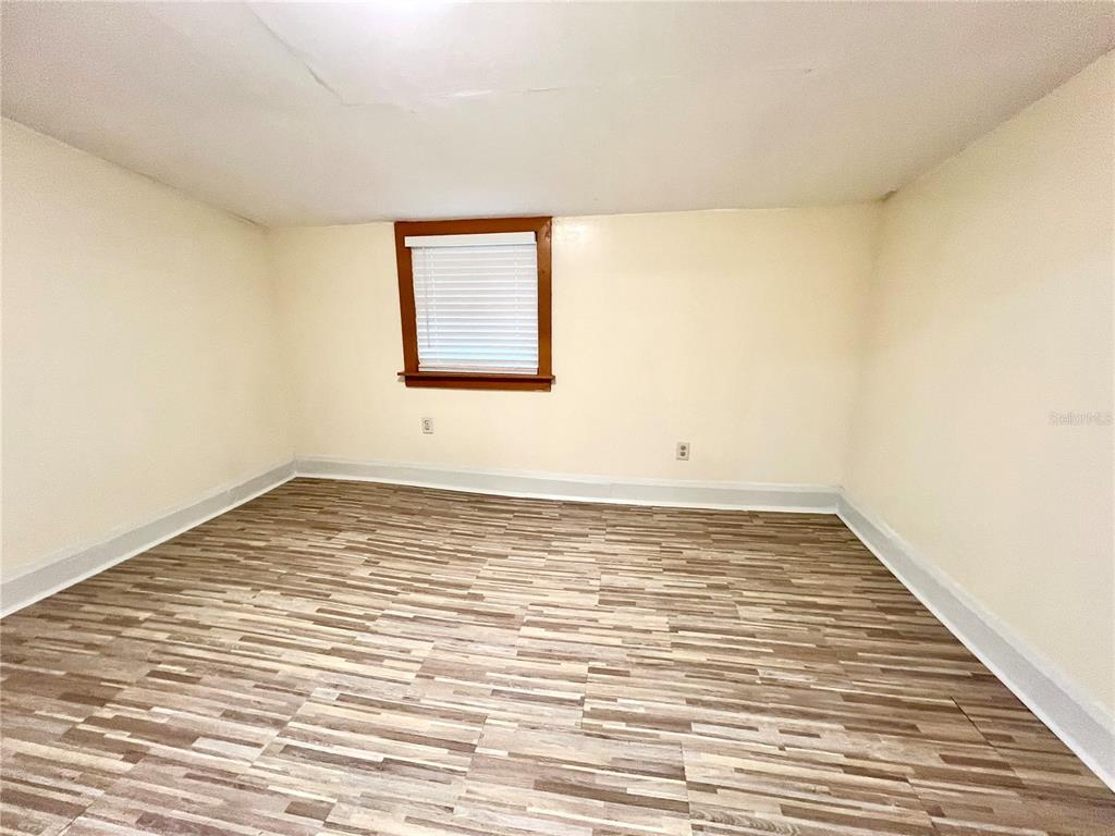 An empty room features light-colored walls, white baseboards, and wood-look laminate flooring — 343 WEAVER AVENUE, LAKE WALES, FL