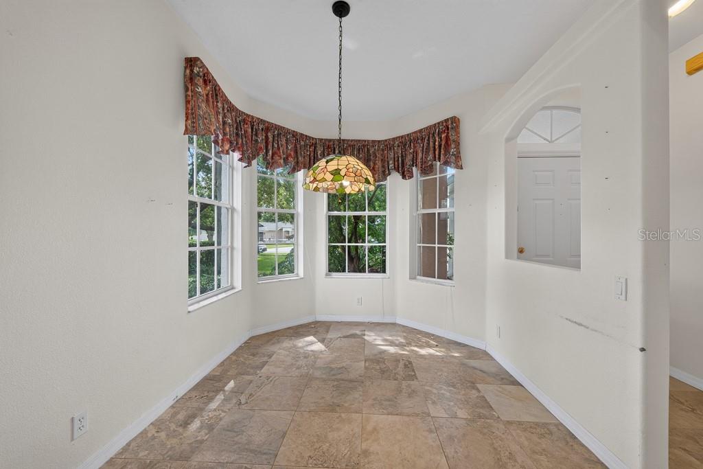 A dining nook features tile flooring, a bay window with a valance, and a pendant light — 4355 BURNBERRY GLEN COURT, SPRING HILL, FL