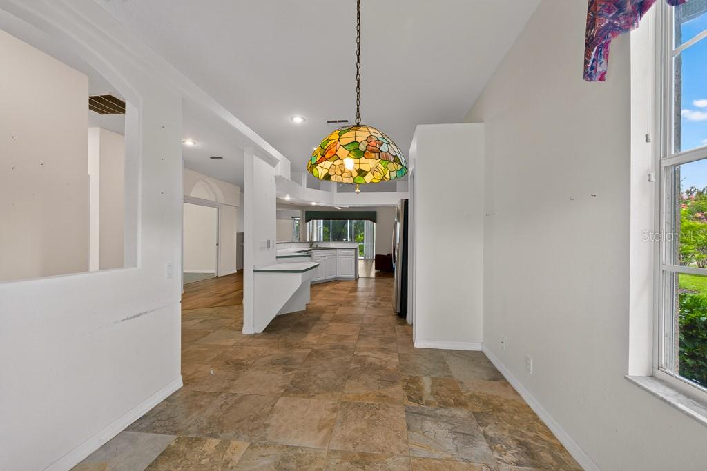 A dining area with tile flooring and a stained-glass pendant light overlooks an open kitchen — 4355 BURNBERRY GLEN COURT, SPRING HILL, FL