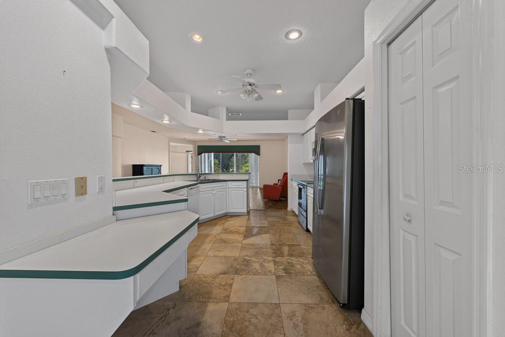 A kitchen with white cabinets, green-trimmed countertops, stainless steel appliances, and tiled flooring — 4355 BURNBERRY GLEN COURT, SPRING HILL, FL