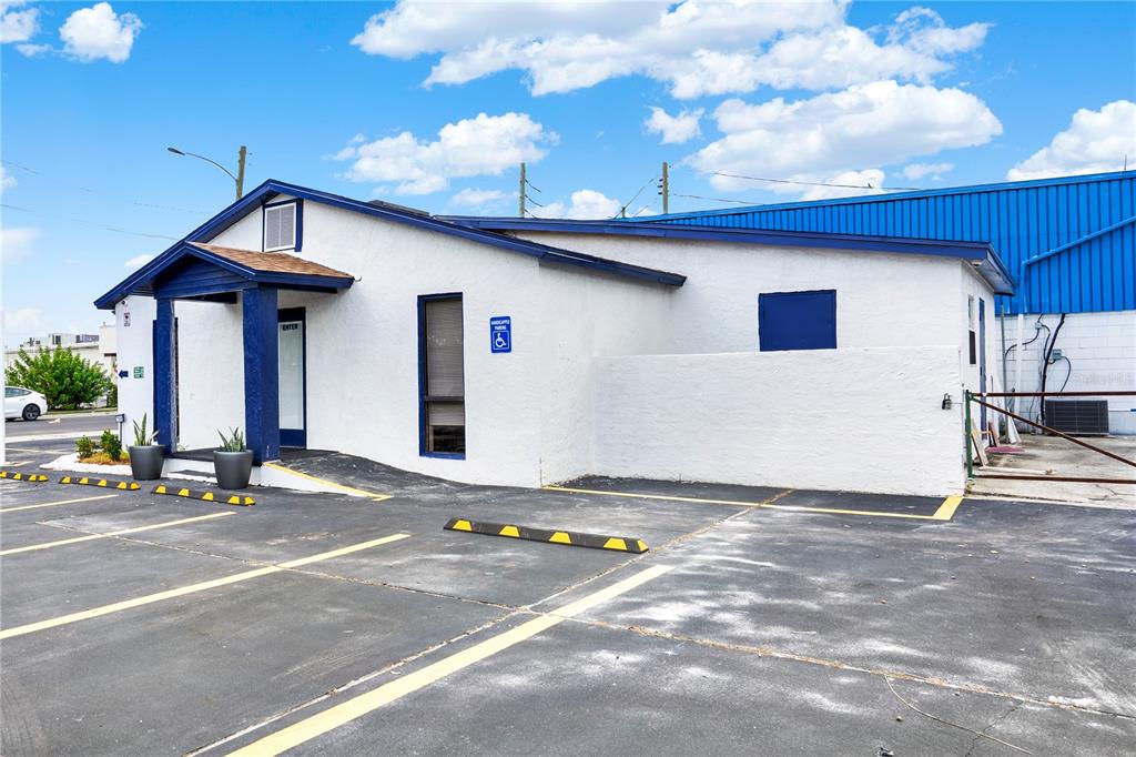 A white, single-story commercial building with a blue-trimmed entrance and an adjacent parking lot — 750 LOWELL BOULEVARD, ORLANDO, FL
