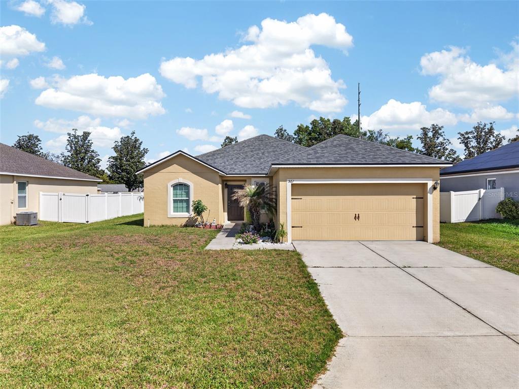 A tan single-story house with a two-car garage and a concrete driveway — 561 LAKE CUMMINGS WAY, LAKE ALFRED, FL