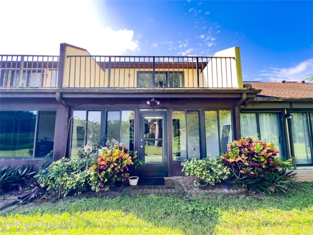 The exterior of a two-story townhouse features a ground-level enclosed patio and an upper balcony — 2193 KINGS CROSS STREET, TITUSVILLE, FL