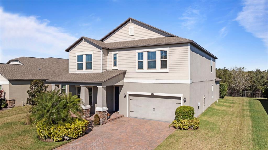 A two-story suburban house features a tan stucco and siding exterior with a paved driveway — 3138 HILLIARD DRIVE, WESLEY CHAPEL, FL