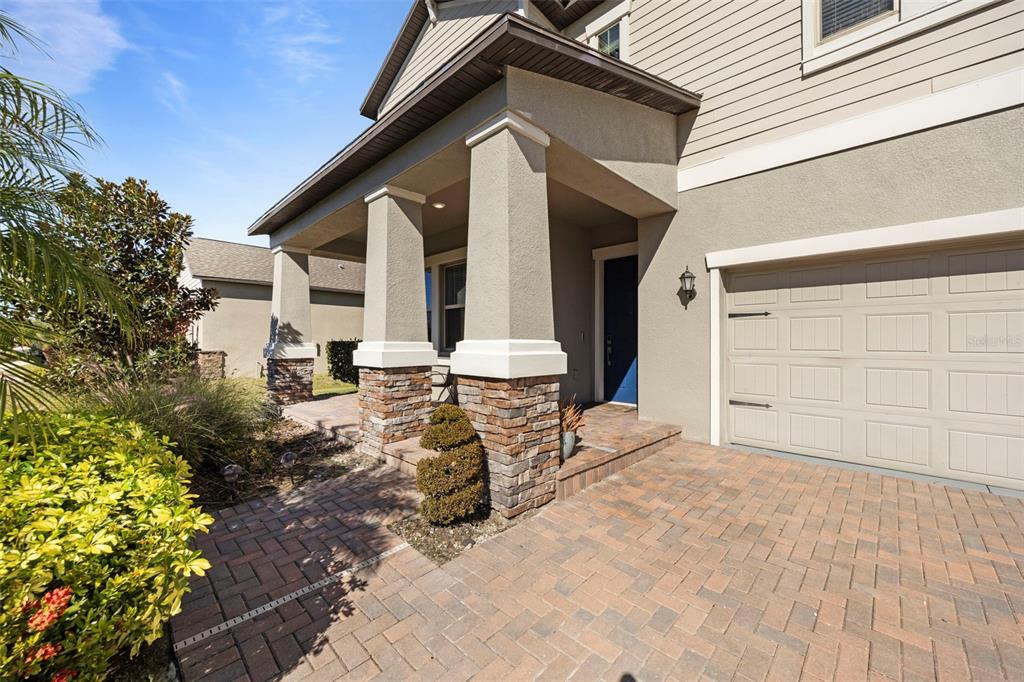 A house exterior features a stone-accented porch, a paved driveway, and a blue front door — 3138 HILLIARD DRIVE, WESLEY CHAPEL, FL