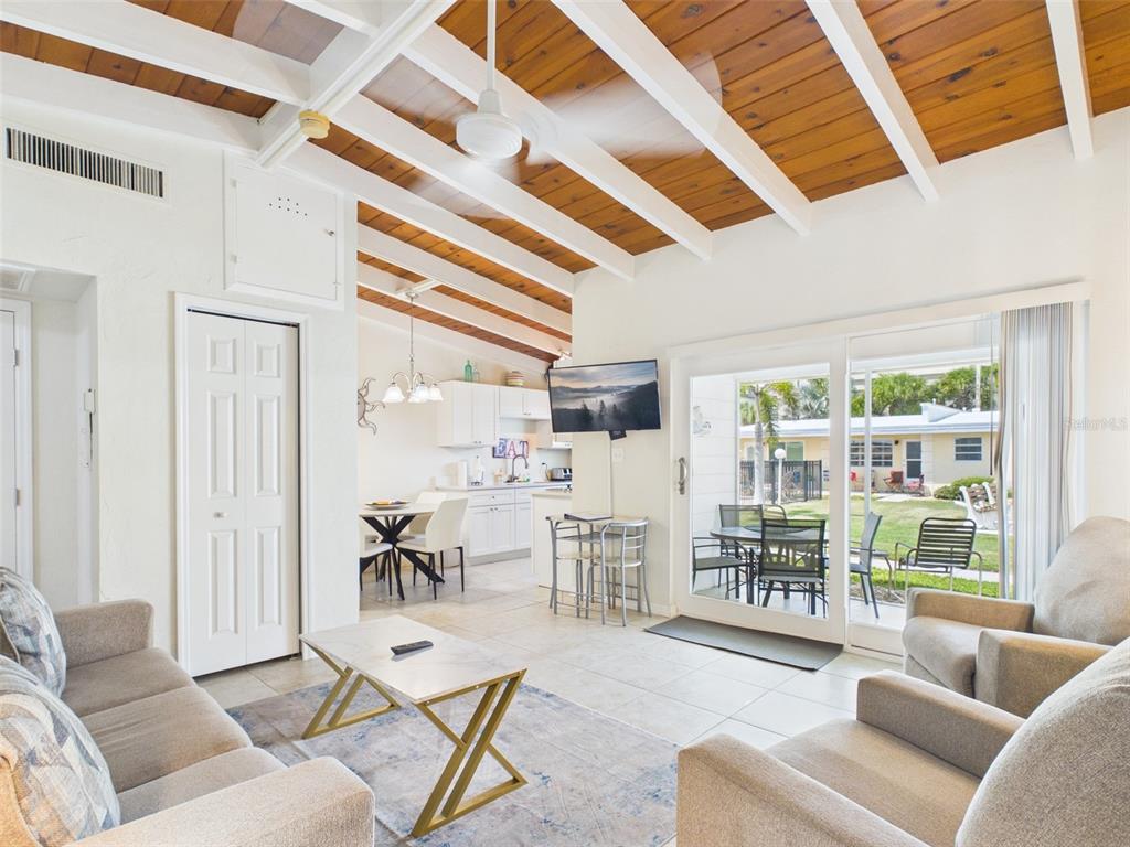 A living room with a wood-beamed ceiling, tile floors, and a sliding door to a patio — 6006 MIDNIGHT PASS ROAD UNIT 51, SARASOTA, FL