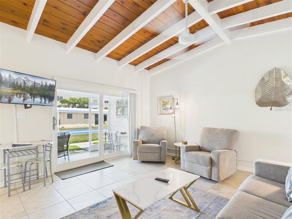 A living room features a vaulted wood-beam ceiling, tile floors, and sliding glass doors — 6006 MIDNIGHT PASS ROAD UNIT 51, SARASOTA, FL
