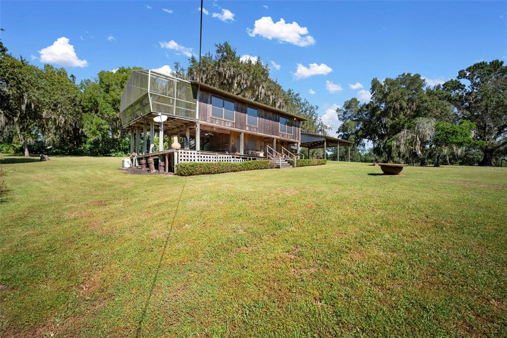 A two-story wooden house with a screened-in porch stands on a large grassy lot — 32854 LISTER ROAD, DADE CITY, FL
