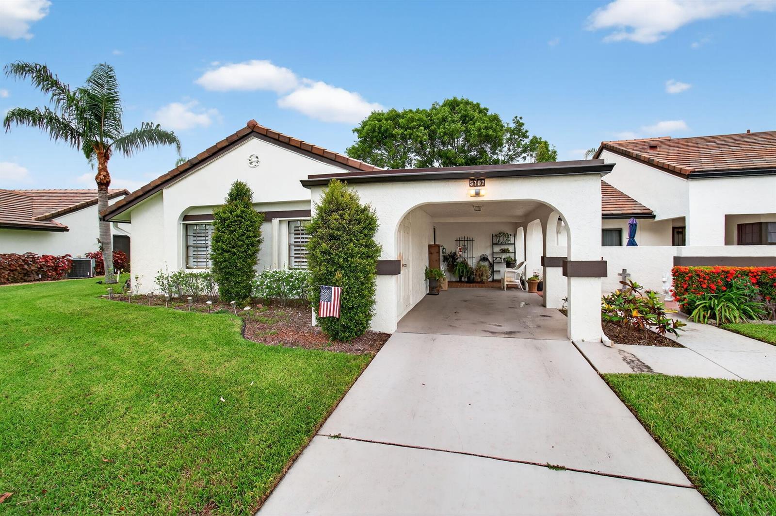 A single-story house with a white stucco exterior, a tiled roof, and a covered carport — 5707 Parkwalk Circle E, Boynton Beach FL 33472, BOYNTON BEACH, FL
