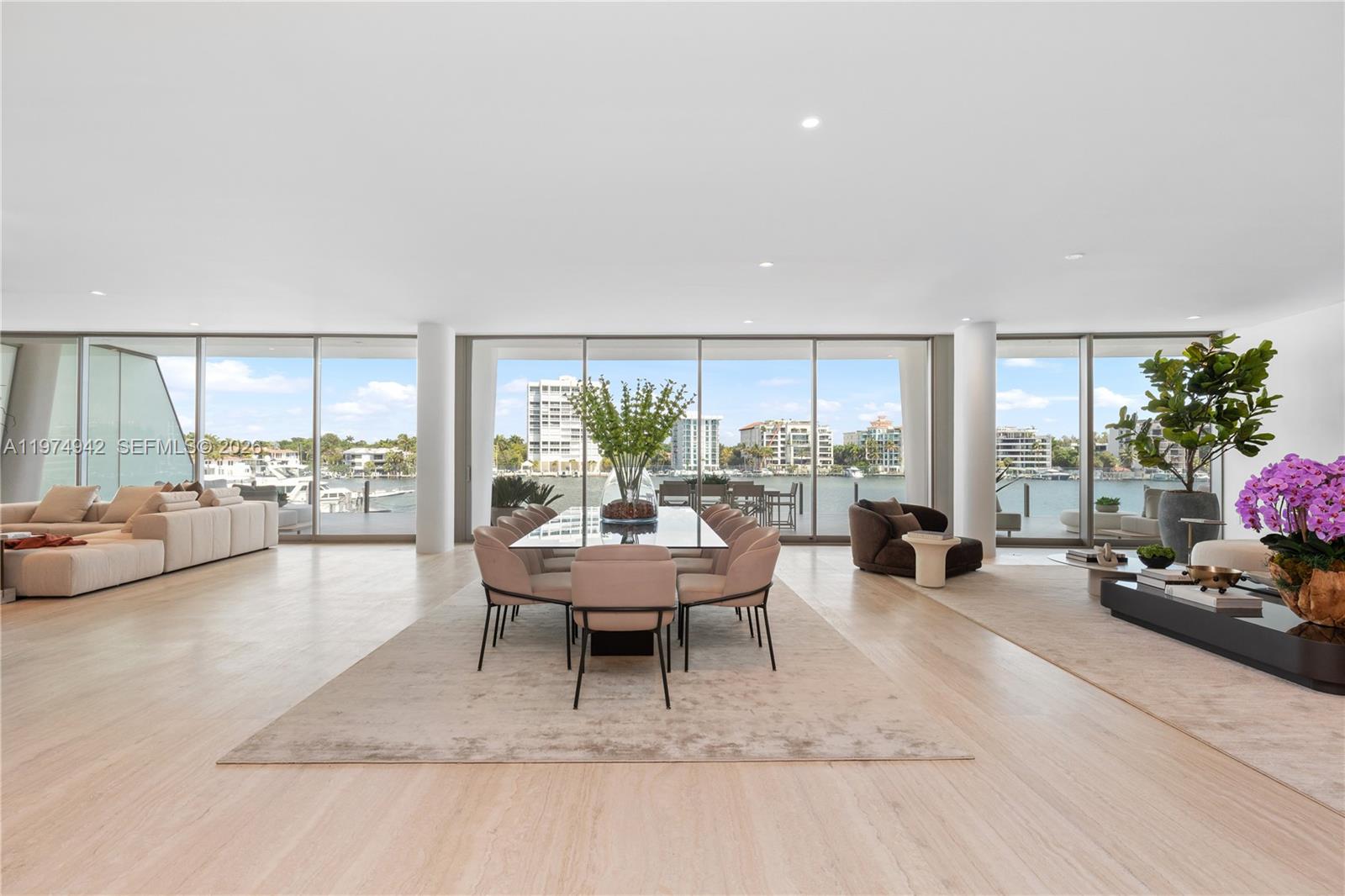 A spacious, open-concept living and dining area features floor-to-ceiling windows overlooking a waterfront view — 5 Grove Isle Dr # S201, Miami FL 33133, MIAMI, FL
