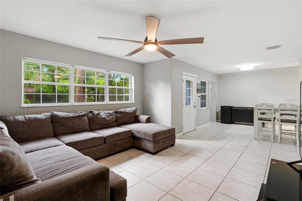 A living room with a gray sectional sofa, tile flooring, and a ceiling fan — 630 NW 35TH TERRACE, GAINESVILLE, FL