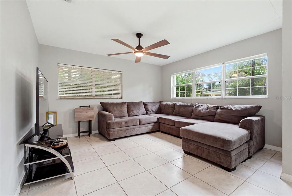 A living room features a large brown sectional sofa, tile flooring, and a ceiling fan — 630 NW 35TH TERRACE, GAINESVILLE, FL