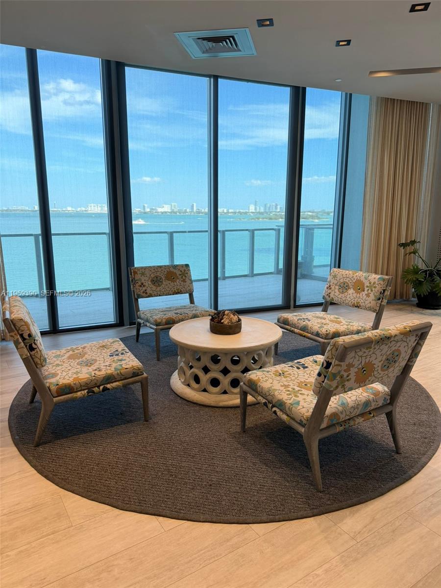 A living area features four patterned chairs around a circular table before floor-to-ceiling windows — 2900 NE 7th Ave # 1205, Miami FL 33137, MIAMI, FL