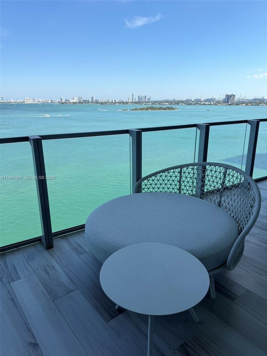 A balcony features a circular lounge chair, a small side table, and a view of the water — 2900 NE 7th Ave # 1205, Miami FL 33137, MIAMI, FL