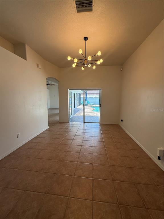 A dining area with tile floors, a modern chandelier, and a sliding door to a pool — 2210 TOWERING OAKS CIRCLE, SEFFNER, FL