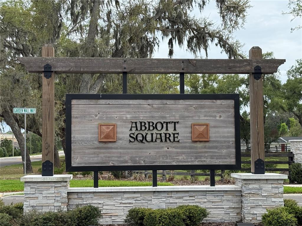 A wooden neighborhood entrance sign for Abbott Square stands on a stone base — 36370 WELL HILL WAY, ZEPHYRHILLS, FL