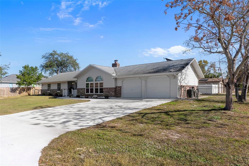 A single-story house with a two-car garage, brick accents, and a concrete driveway — 4286 BLUEWATER AVENUE, SPRING HILL, FL