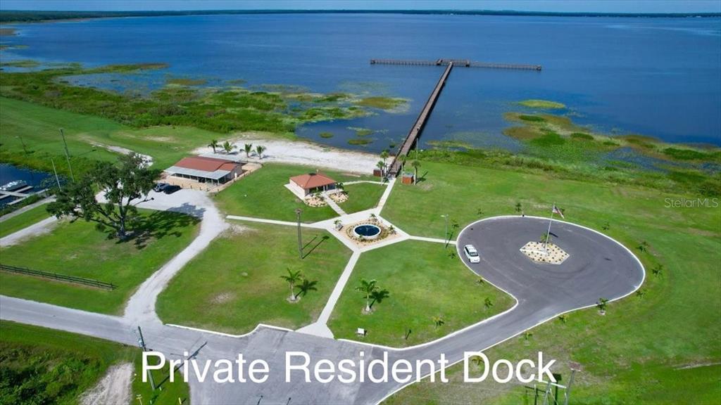 An aerial view shows a long wooden dock extending into a lake from a grassy property — 0 LAGUNA DRIVE, INDIAN LAKE ESTATES, FL
