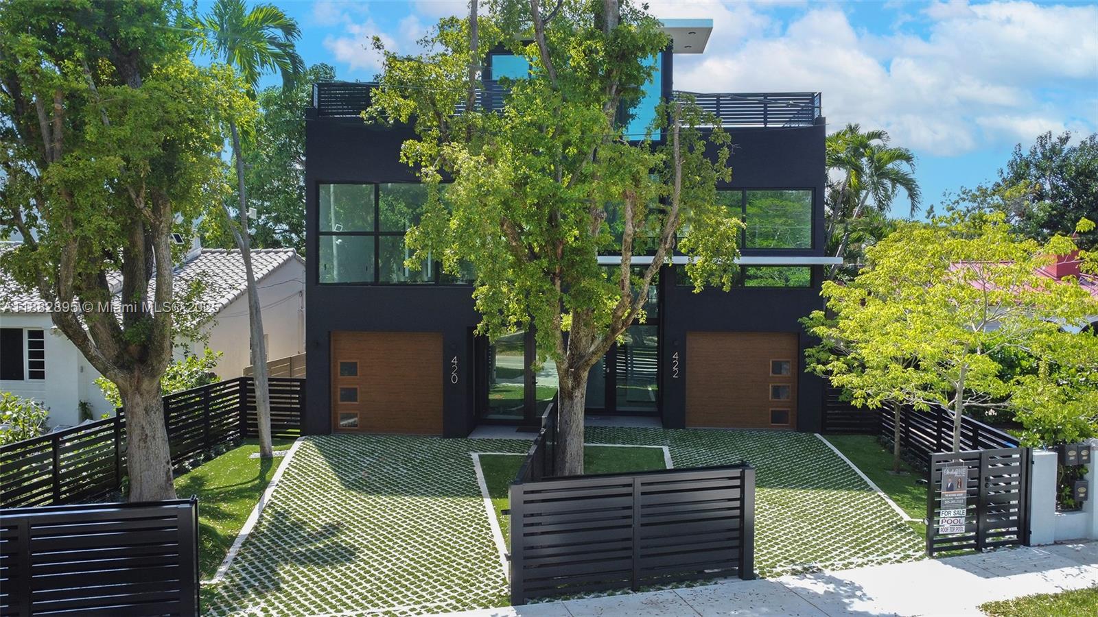 A modern black duplex features wood-paneled garage doors, large windows, and a paved front yard — 420 SW 15th Rd, Miami FL 33129, MIAMI, FL