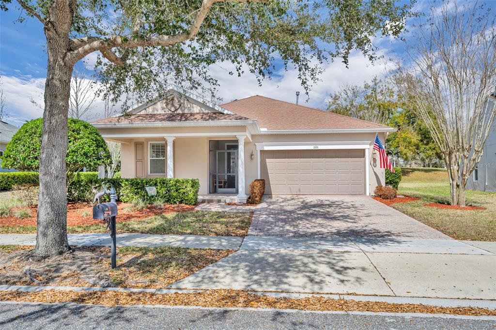 A single-story house with a beige exterior, a two-car garage, and a front porch — 115 SALT MARSH LANE, GROVELAND, FL