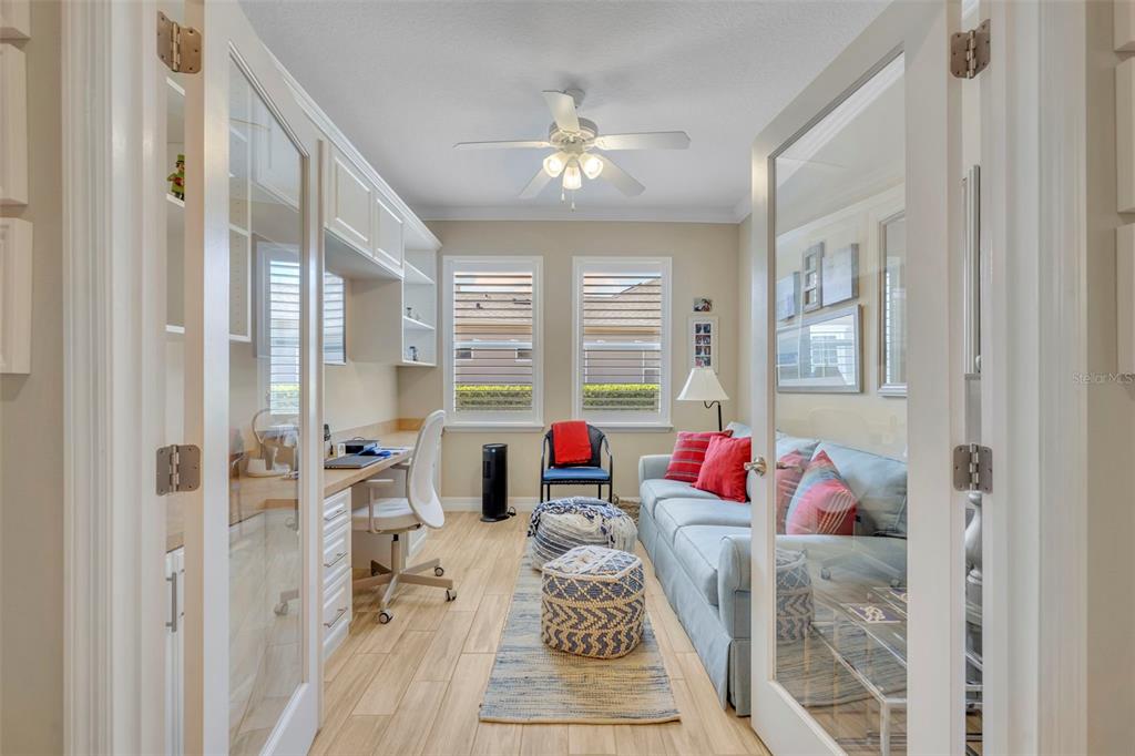 A home office with a desk, sofa, and glass French doors on light wood flooring — 115 SALT MARSH LANE, GROVELAND, FL