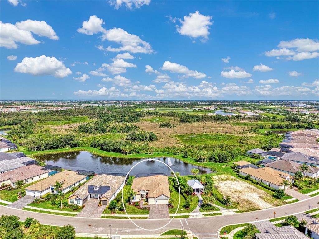 An aerial view of a suburban house with a pool cage beside a lake — 18045 HOME RUN DRIVE, VENICE, FL
