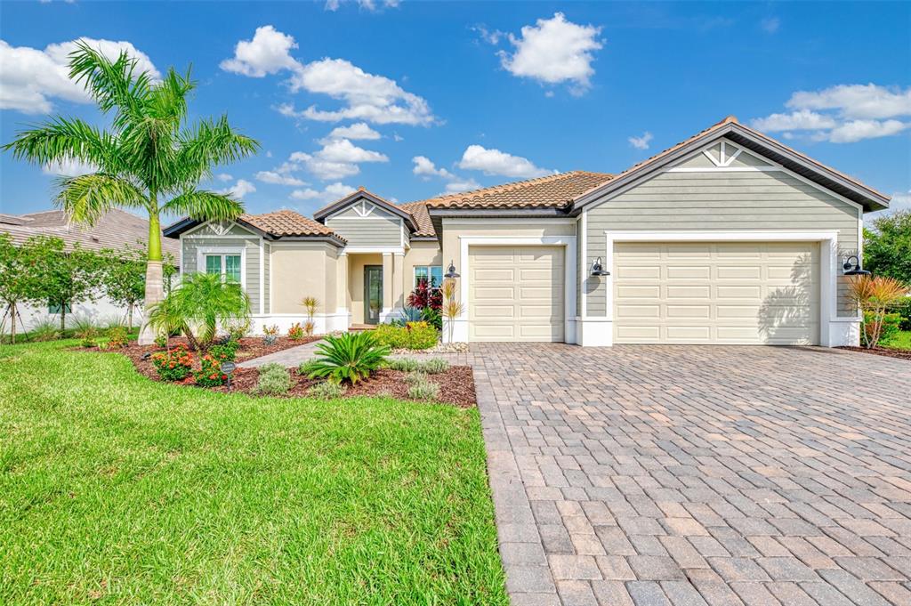 A single-story house with a paved driveway, two-car garage, and a palm tree in front — 18045 HOME RUN DRIVE, VENICE, FL