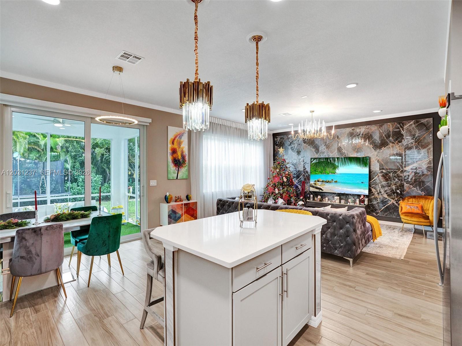 An open-concept kitchen and living area features a white island, marble wall, and dining space — 4414 Ficus St, Hollywood FL 33021, HOLLYWOOD, FL