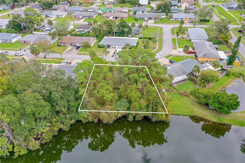 An aerial view shows a vacant, tree-covered residential lot bordering a small lake — TBD TUMBLEWEED TRAIL, PORT ORANGE, FL