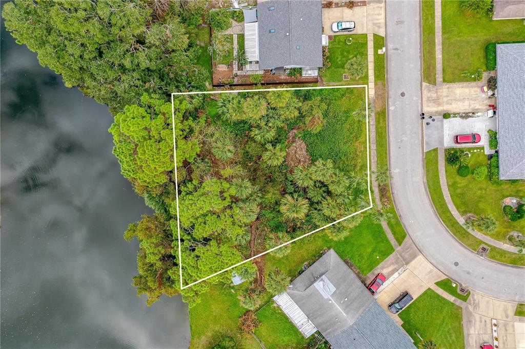 An aerial view shows a vacant, wooded residential lot situated between two houses and water — TBD TUMBLEWEED TRAIL, PORT ORANGE, FL