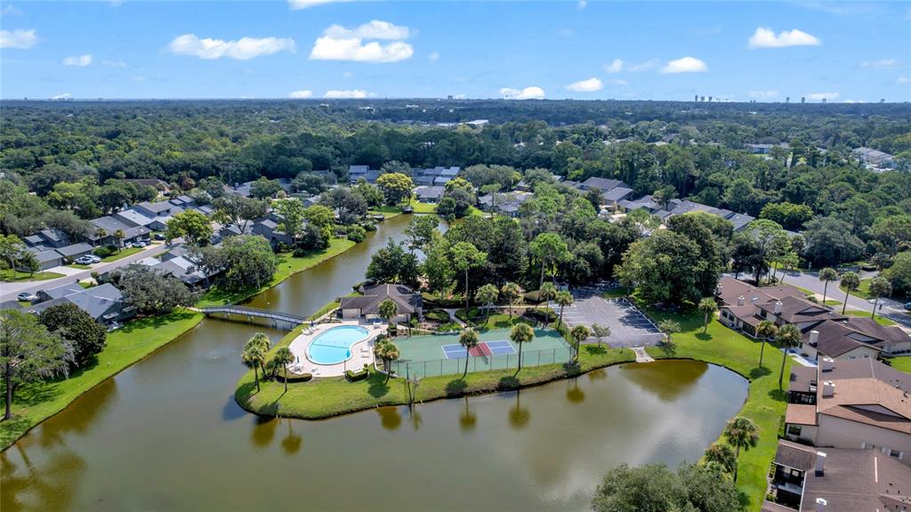 An aerial view shows a community pool and tennis court situated on a small island — 172 DEER LAKE CIRCLE, ORMOND BEACH, FL