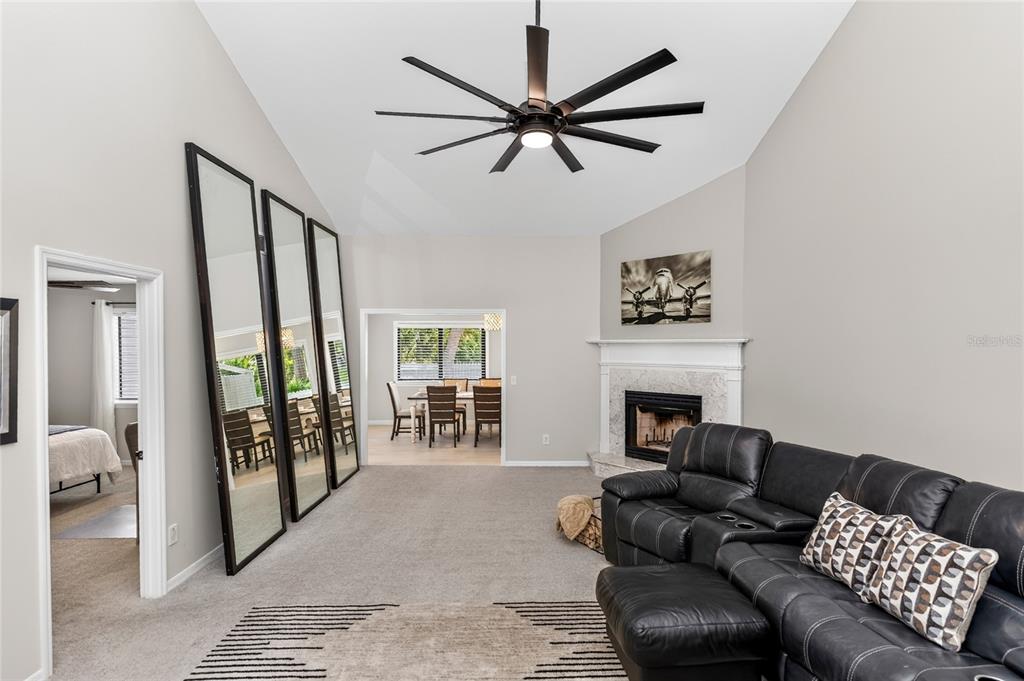 A living room with a vaulted ceiling, black leather sectional, fireplace, and three large floor mirrors — 172 DEER LAKE CIRCLE, ORMOND BEACH, FL