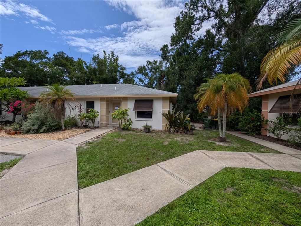 A single-story residential building with a concrete walkway, palm trees, and landscaping — 638 N JEFFERSON AVENUE UNIT 15, SARASOTA, FL